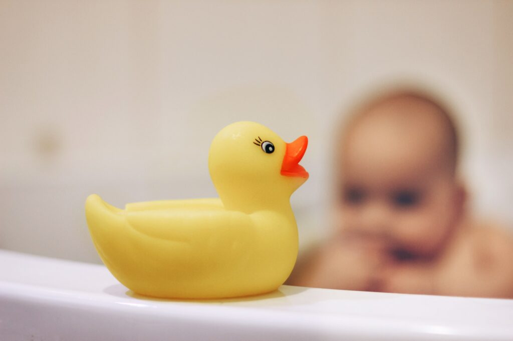 Baby bathing with yellow rubber duck
